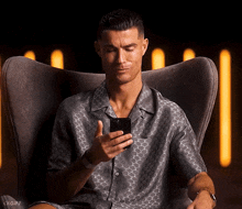 a man sitting in a chair looking at his phone
