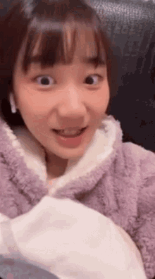 the girl is wearing a purple sweater and white earbuds .