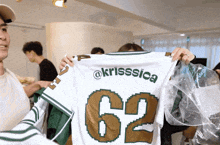 a person holding up a jersey that says krisssica and the number 62