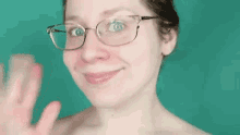 a woman wearing glasses is waving at the camera .