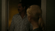 a man in a floral shirt stands next to a blonde woman