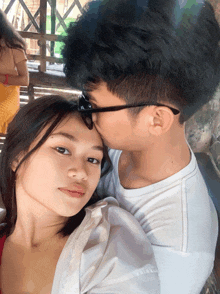 a man kissing a woman on the forehead while wearing glasses