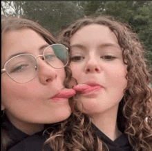 two girls wearing glasses stick their tongues out