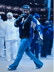 a man wearing a blue jacket with the letter t on it is singing into a microphone