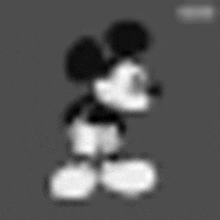 a black and white photo of mickey mouse on a grey background .