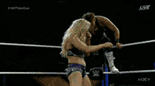 two women are wrestling in a ring with a sign that says " your wife " in the background
