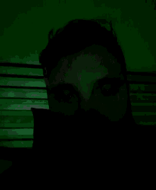 a man 's face is shown in a dark room with a green background
