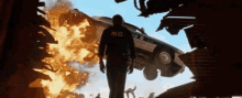 a police officer is standing in front of a burning police car