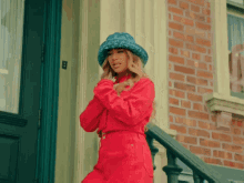 a woman wearing a red jacket and a blue hat is standing on a set of stairs