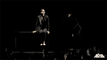 a woman in a black suit is sitting next to another woman in a black suit and the word aria is on the bottom