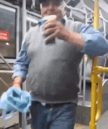 a man in a gray vest and blue shirt is holding a blue cloth