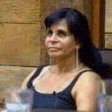 a woman is sitting at a table with a glass of water and a microphone in her ear .