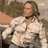 a man wearing a shirt with horses on it is sitting in a car