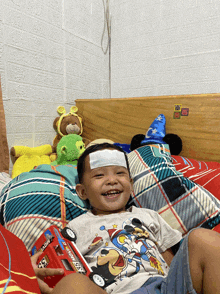 a little boy with a sticker on his forehead that says ' sick ' on it is holding a toy car