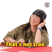 a woman sitting at a table with the words that 's not true
