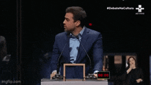 a man giving another man a high five in front of a podium that says #debatenacultura
