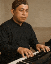 a man in a black shirt plays a piano