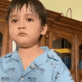 a young boy wearing a blue shirt is making a funny face .