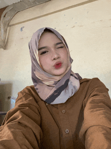 a woman wearing a hijab is taking a selfie
