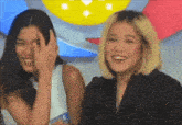 two women are posing for a picture and one of them has a sticker on her shirt that says ' a ' on it