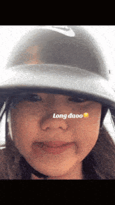 a girl wearing a helmet has the word long on her nose
