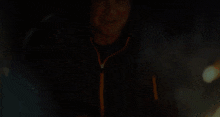 a man wearing a black jacket with an orange zipper