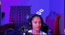 a person wearing headphones is sitting in front of a microphone in a room .