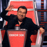 a man sitting in a chair with a red button that says error 30k on it