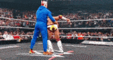 a man in a blue jumpsuit is helping a wrestler in a ring