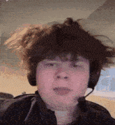 a boy wearing headphones and a microphone looks at the camera
