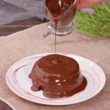 a person pouring chocolate sauce on a dessert on a plate