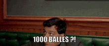 a man in a suit is sitting on a green couch and says 1000 balls ?