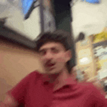 a blurry picture of a man in a red shirt standing in a store .