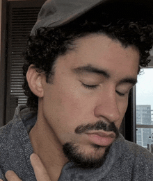 a man with curly hair and a beard is wearing a baseball cap