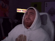 a man in a white hoodie is sitting in a chair
