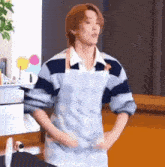 a man wearing an apron and a striped shirt is dancing in a kitchen .
