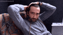a man with a beard is sitting on a couch with his hands behind his head and the hashtag @itsscottiesstark above him