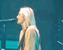 a woman is singing into a microphone on a stage without a shirt on .