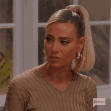 a woman with a ponytail and earrings is wearing a bravo shirt