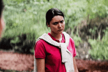 a woman wearing a red polo shirt and a white sweater around her neck is making a funny face .