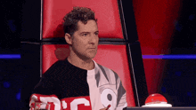 a man with curly hair is sitting in a red chair .