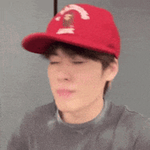 a young man wearing a red hat and a grey shirt