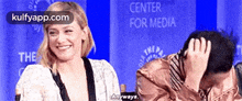 a man and a woman are laughing in front of a sign that says center for media