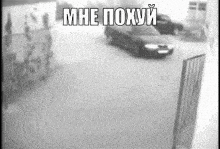 a black and white photo of a car driving down a street with russian writing on it .