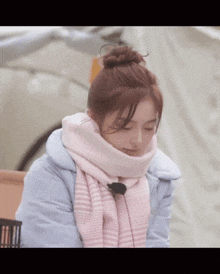 a woman wearing a scarf and a jacket is looking down