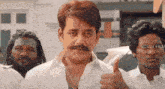 a man with a mustache is giving a thumbs up in front of a group of people .