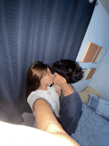 a man and woman are kissing in front of a blue curtain