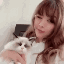 a woman is holding a cat in her arms and smiling at the camera .