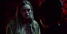 a woman is standing next to another woman in a dark room and talking to her .