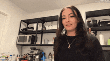 a woman stands in a kitchen with a microwave and a sign that says daily subs at the top